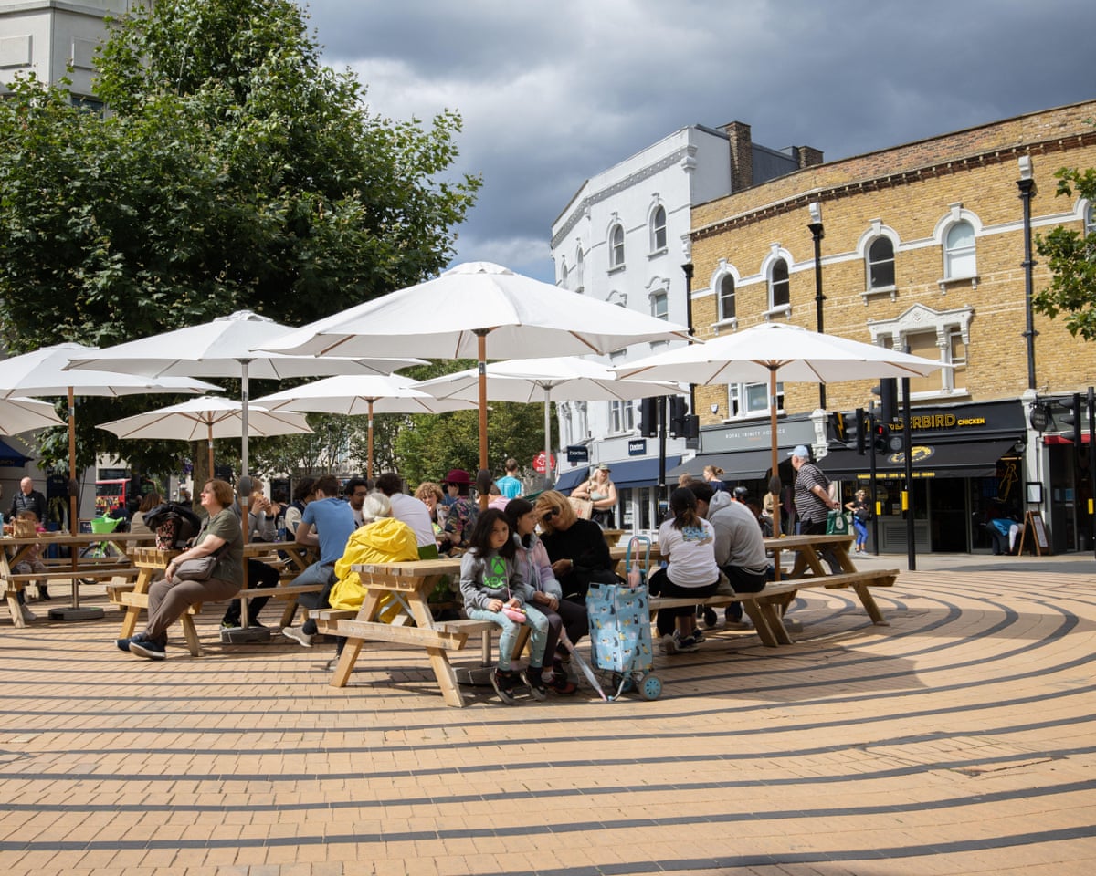 People sitting outside enjoying the warm weather at Wimbledon’s main Broadway shopping area in southwest London in 2025.