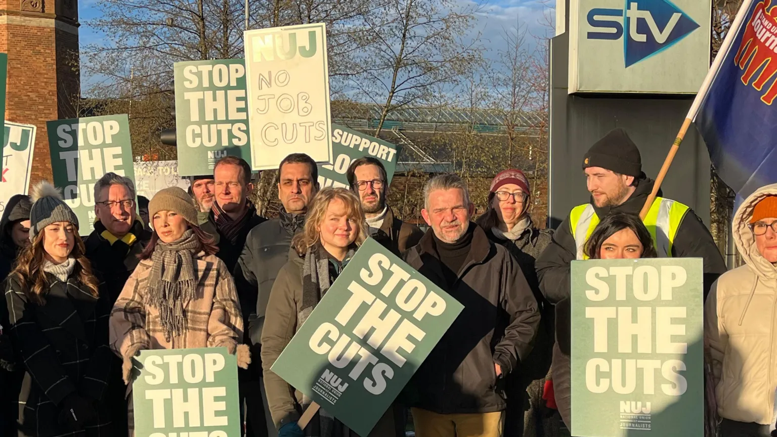 STV staff wearing winter clothing holding placards on a picket line in Glasgow. The signs read 
