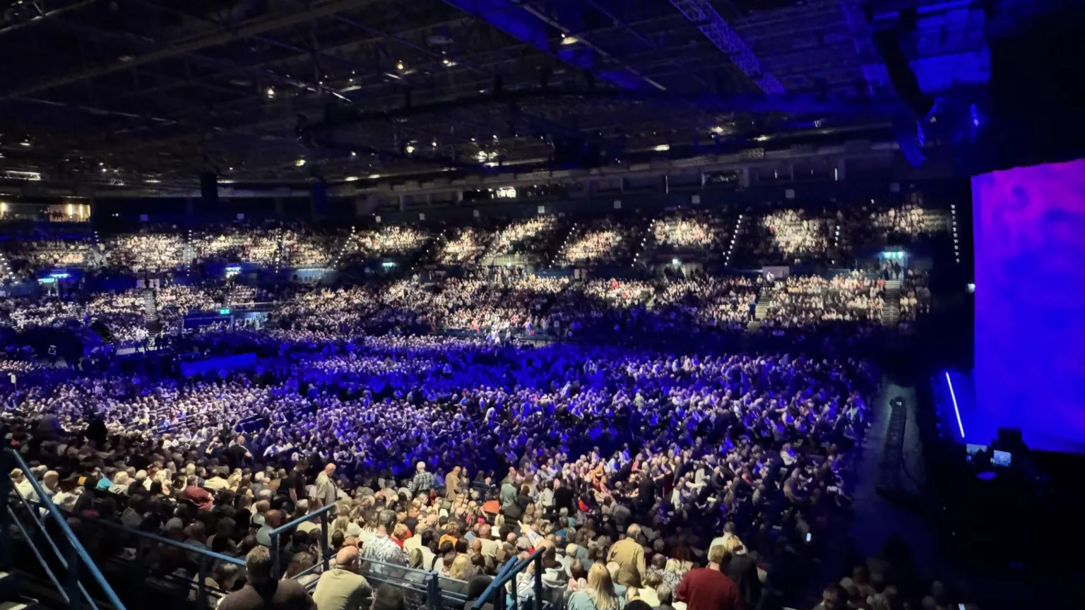 A wide photo of an indoor arena with many people inside.