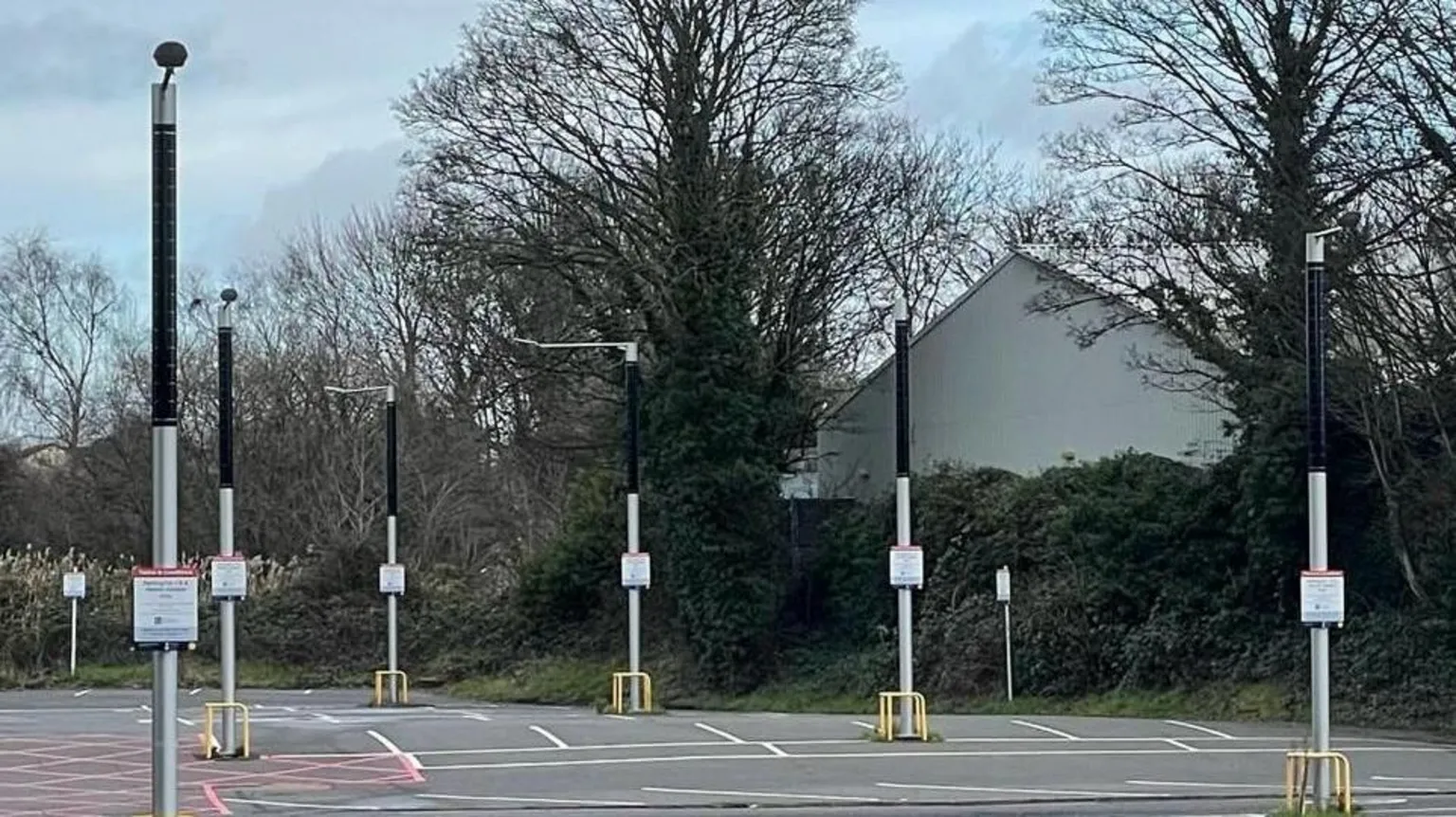 Conflow Power Group A car park in which iLamps are visible - the lamps have dark cylindrical solar cells at the top and a yellow metal frame protects the base