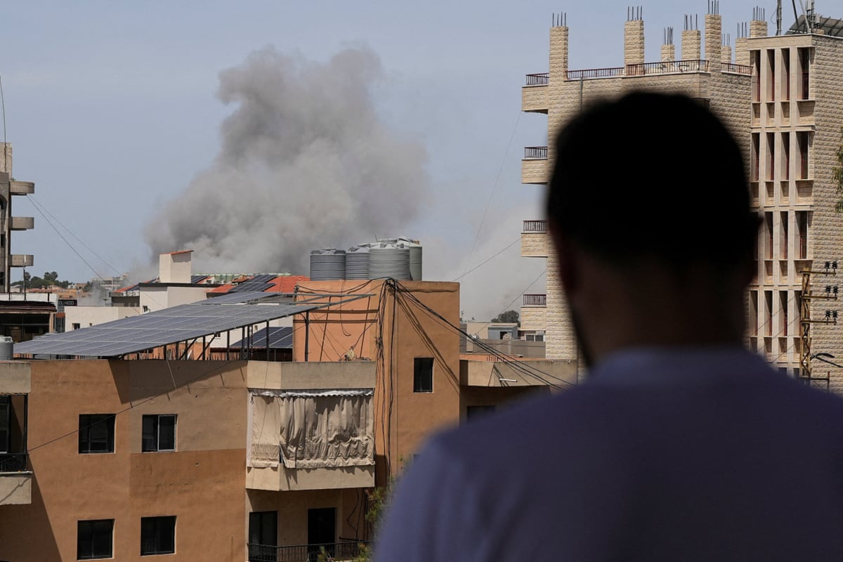 A man watches smoke rising in the distance.