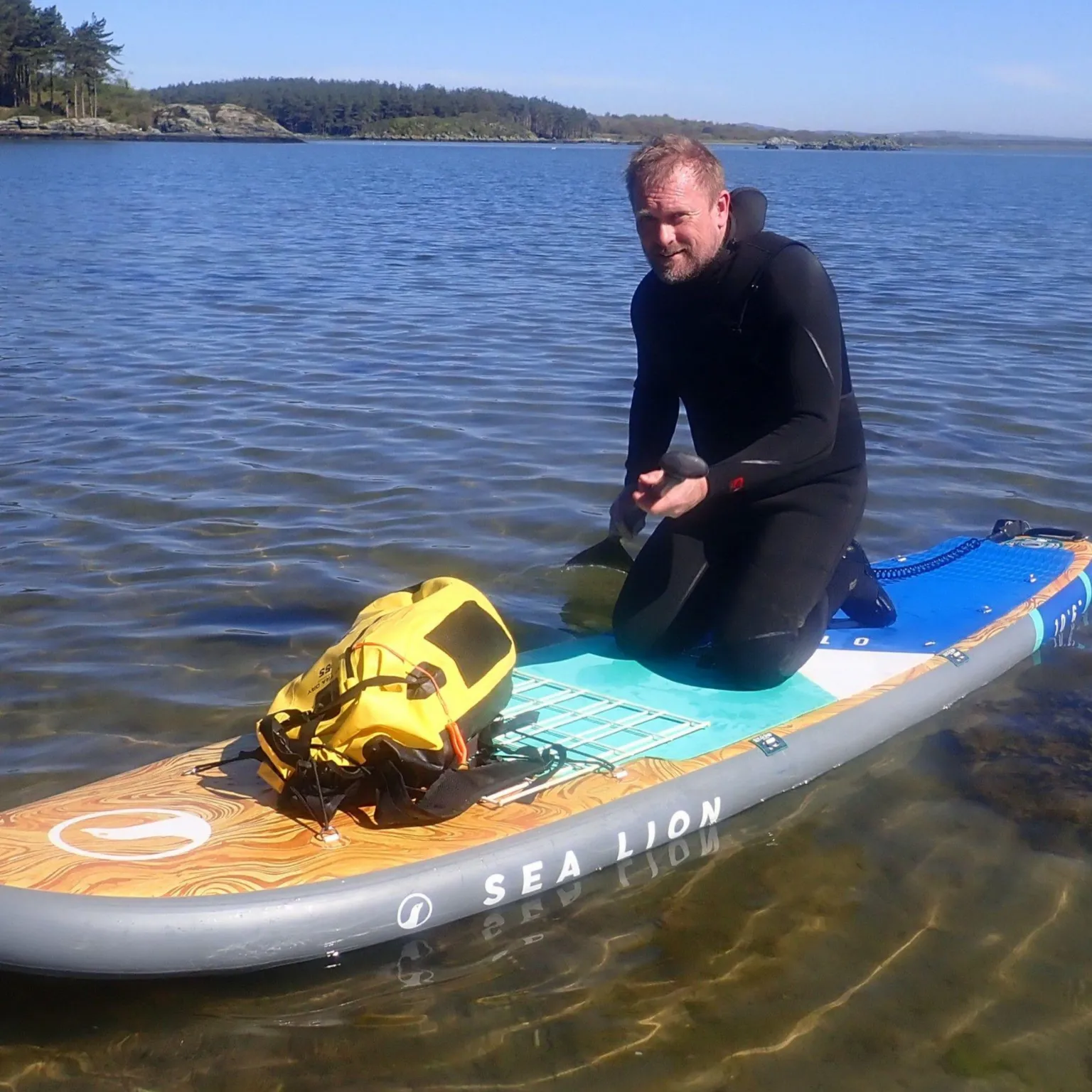 Swansea University Dr Richard Unsworth of Swansea University sat on a surfboard in a black wetsuit in shallow water at sea