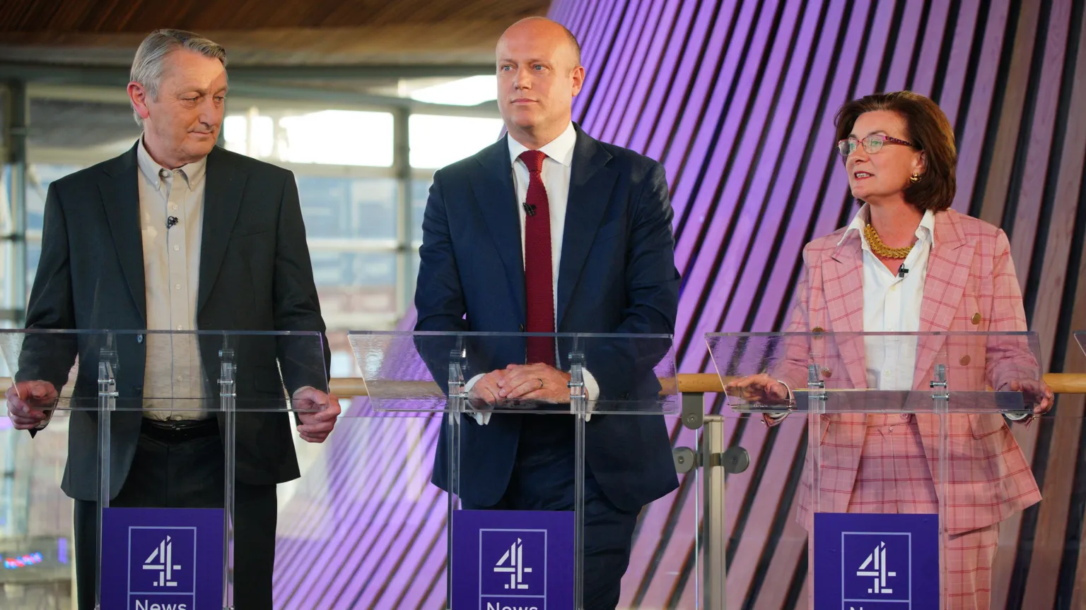 Three people - Anthony Slaughter, Dan Thomas, Eluned Morgan, stood next to each other in front of lecterns 