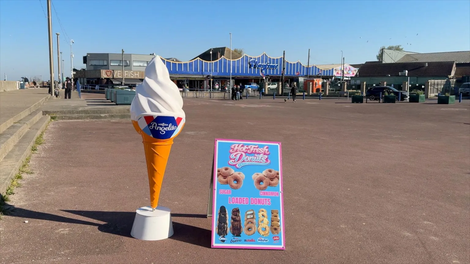 A photo of the Isle of Sheppey sea front, including a large plastic ice cream and a donut advertising board.