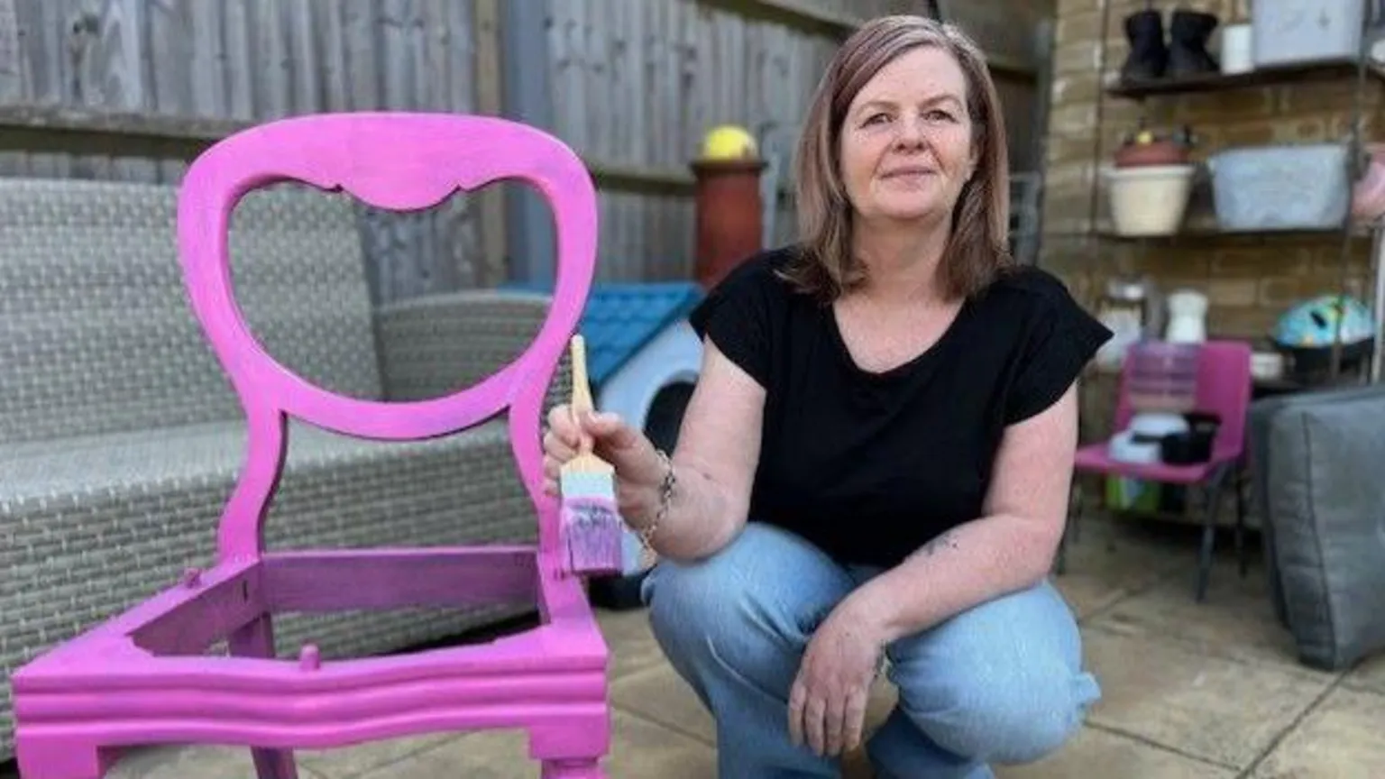Paula Desai, a furniture restorer and novelty card maker, paints a pink chair.