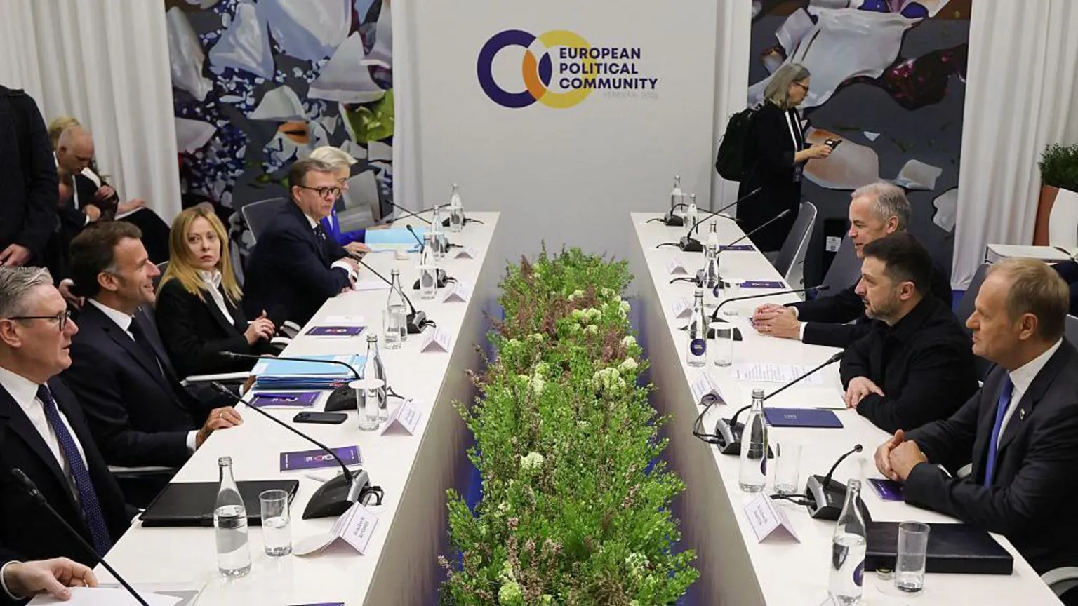 AFP via The leaders sit at two tables facing one another, with microphones and documents on the table in front of them 