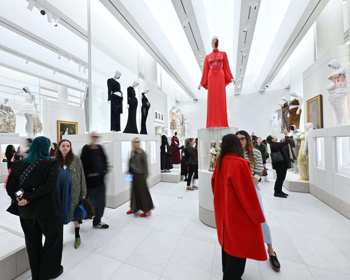 A large high-ceilinged hall with fashion pieces displayed on pedestals