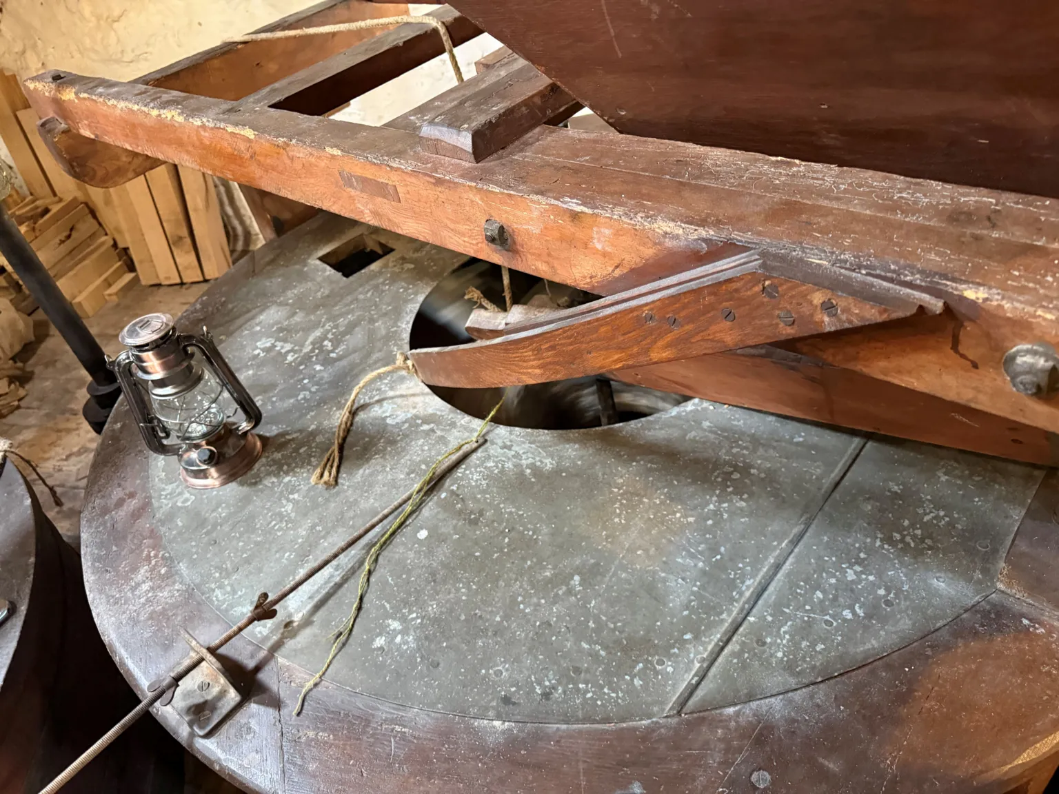  A grey circular stone with a wooden pole lying across it makes up the millstone.