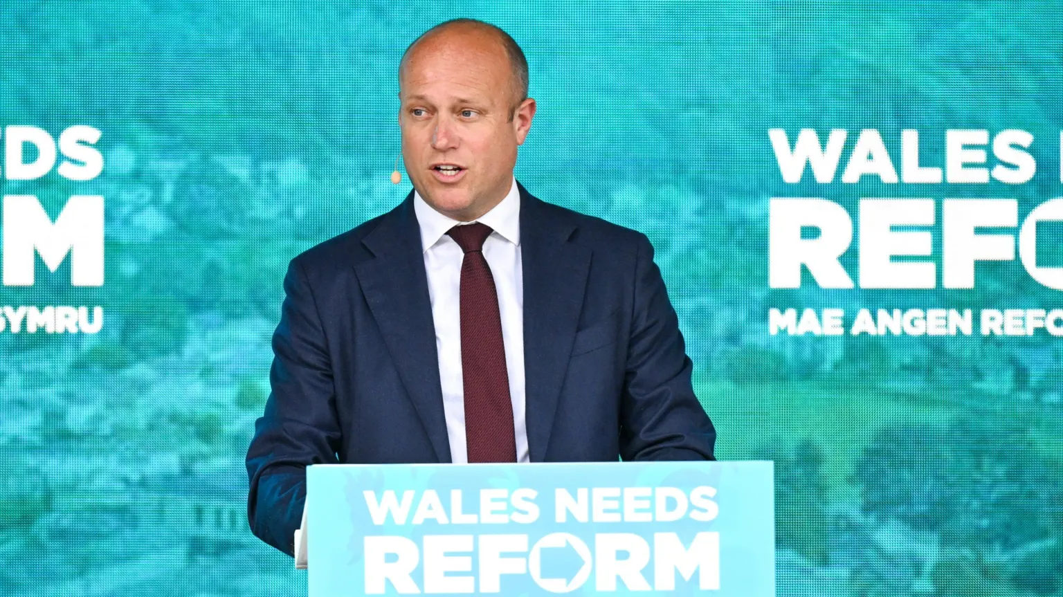  Dan Thomas stands at a lectern with Reform branding