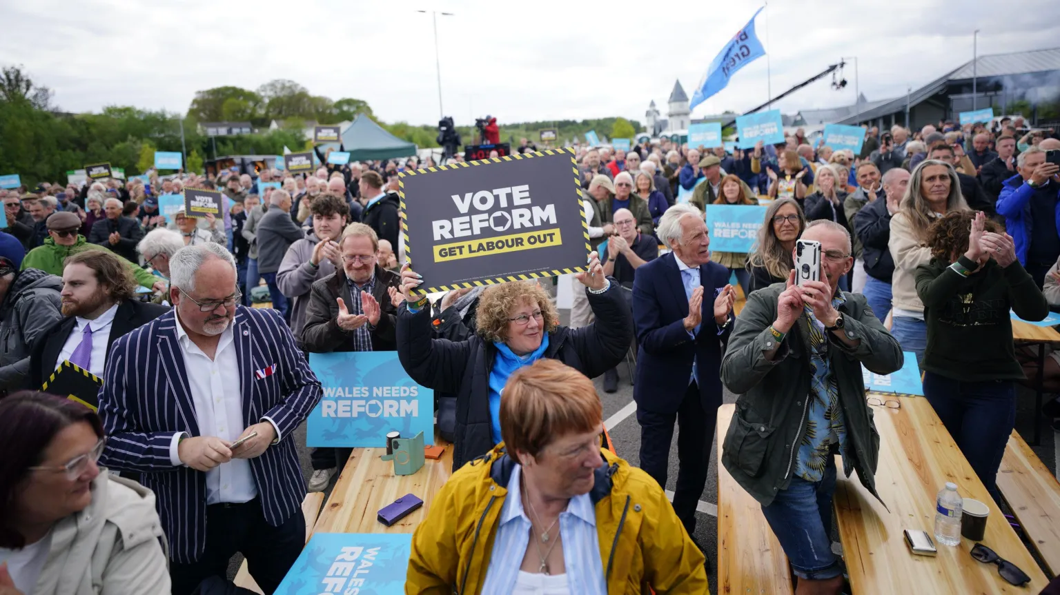 A group of people stood around benches holding up placards