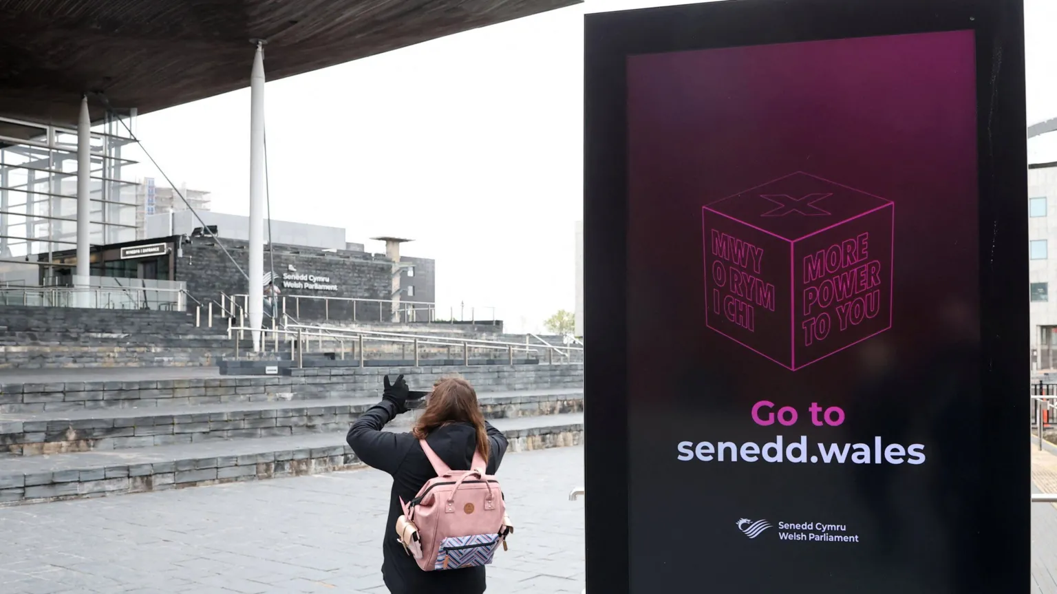  A person takes images beside an election information sign outside of the Senedd