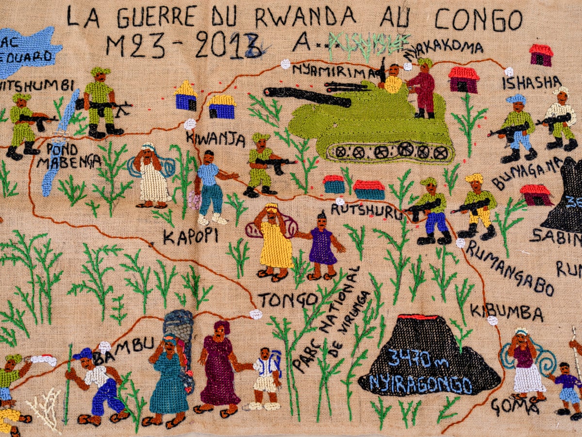 A tapestry scene of war in the DRC with the title La Guerre du Rwanda au Congo: M23 – 2013 sewn on it. 