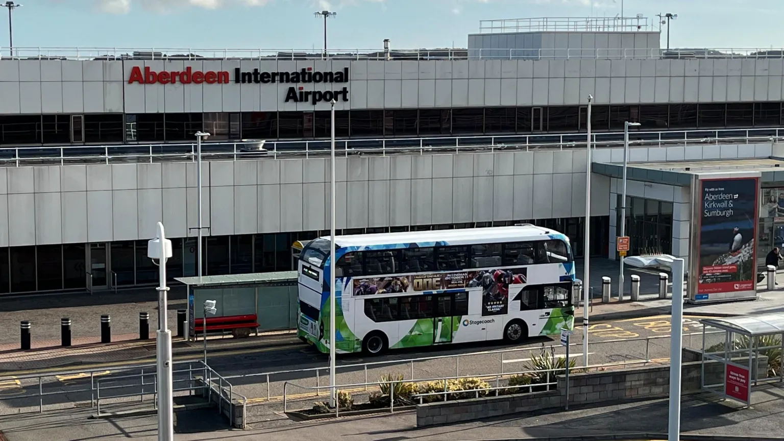 Main entrance of Aberdeen Airport. A double decker bus is on the road outside of the entrance. 