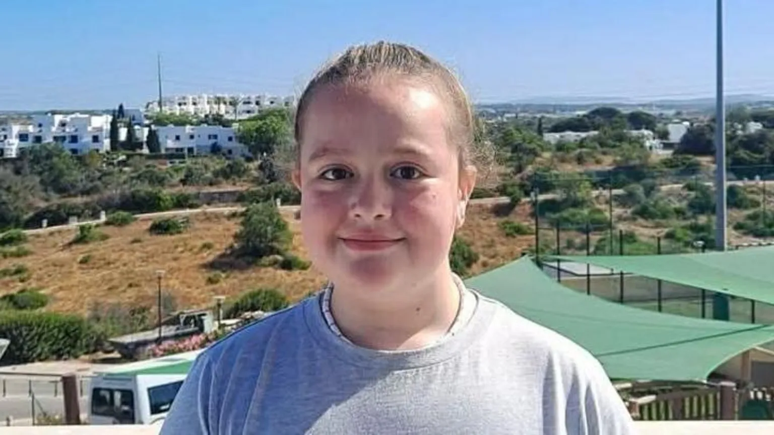 Evanna Kirkpatrick Eryn has her long brown hair tied back and is wearing a grey T-shirt. She is standing on a balcony overlooking some sport pitches and buildings. 