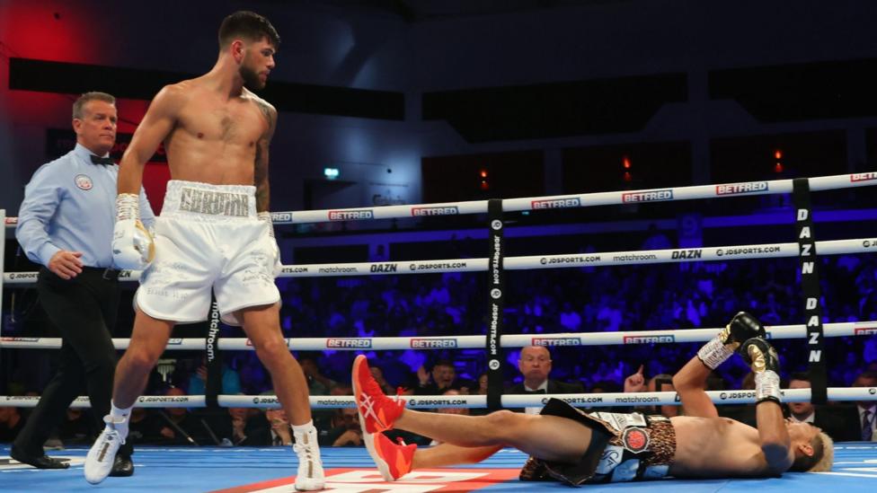 Joe Cordina stands over Kenichi Ogawa lying flat on the canvas