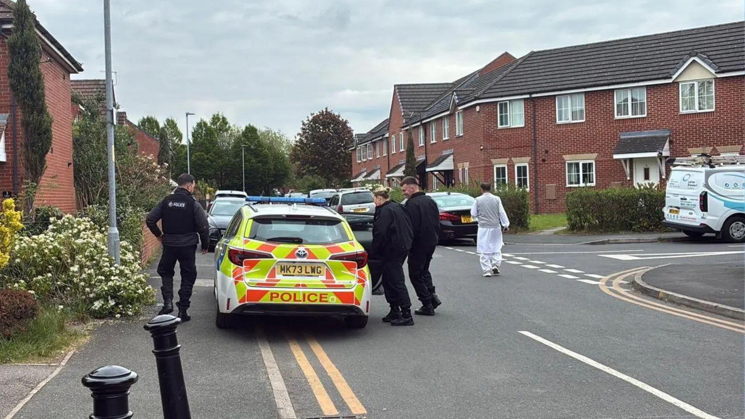 Three police officers are getting into a police car outside the school. 