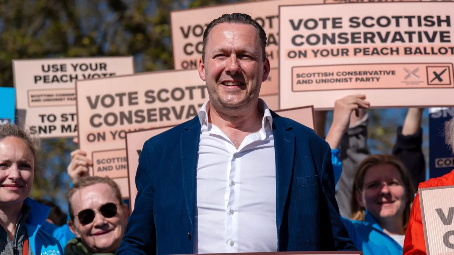  Russell Findlay standing in front of a number of supporters holding up peach ballot papers.