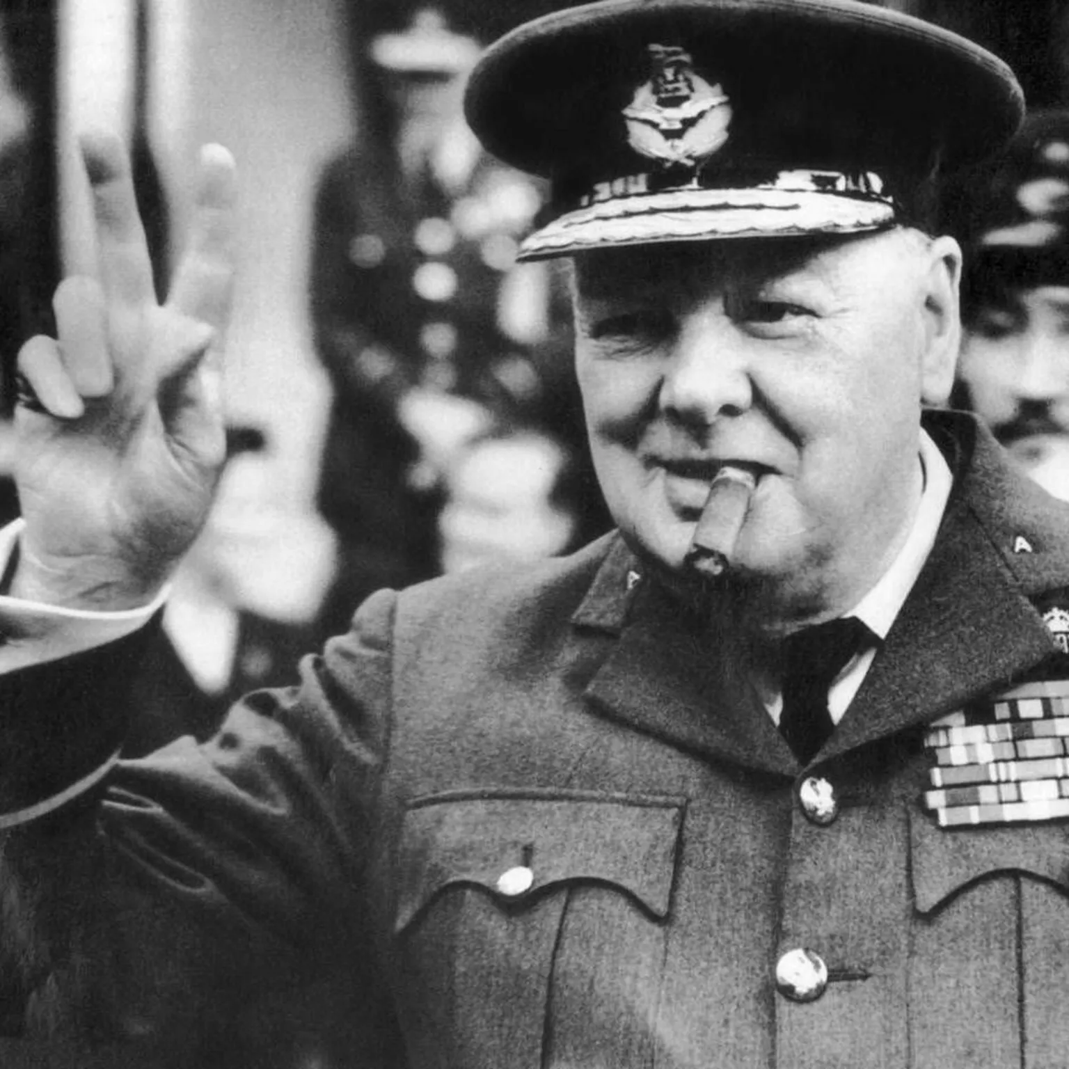  Winston Churchill, wearing an RAF uniform, with cigar in mouth, does his characteristic V for victory salute