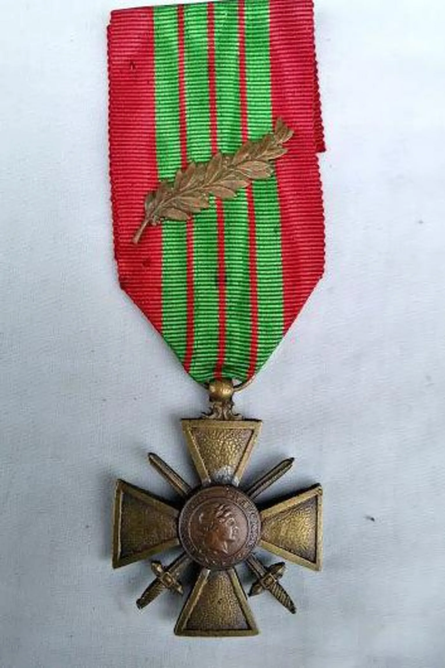 Imperial War Museum A gold medal in the shape of a crucifix with two crossing blades, is attached to a red ribbon with four vertical green stripes