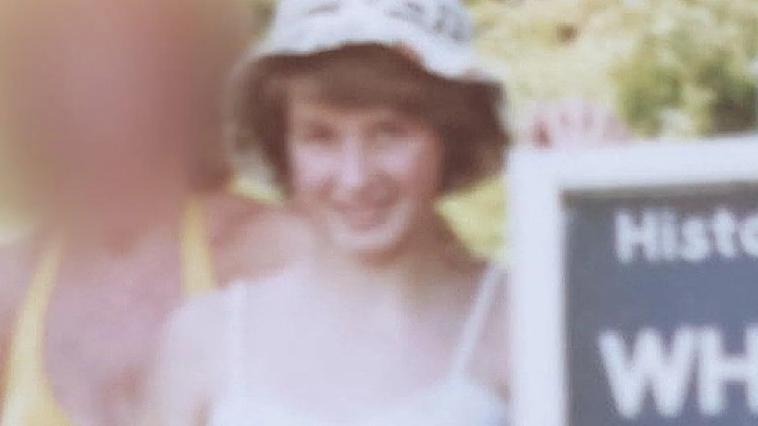Nicola Bannon An old picture of a young girl with short brown hair. She is wearing a floral sun hat and a white top with thin straps. 
