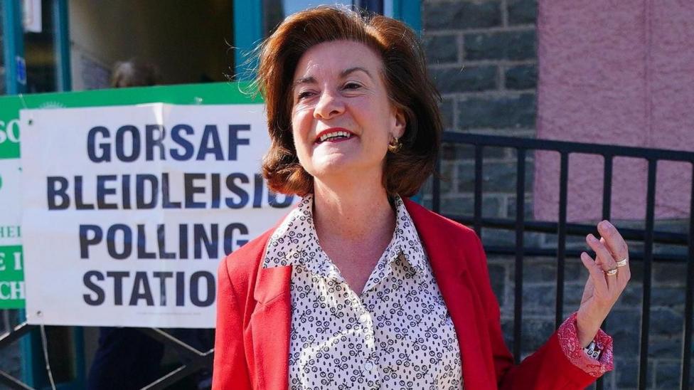 Eluned Morgan o flaen gorsaf bleidleisio