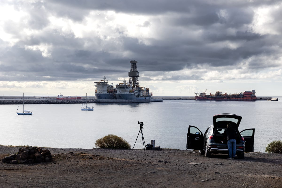 A member of the press sets up a camera overlooking the port, which is mostly empty of ships