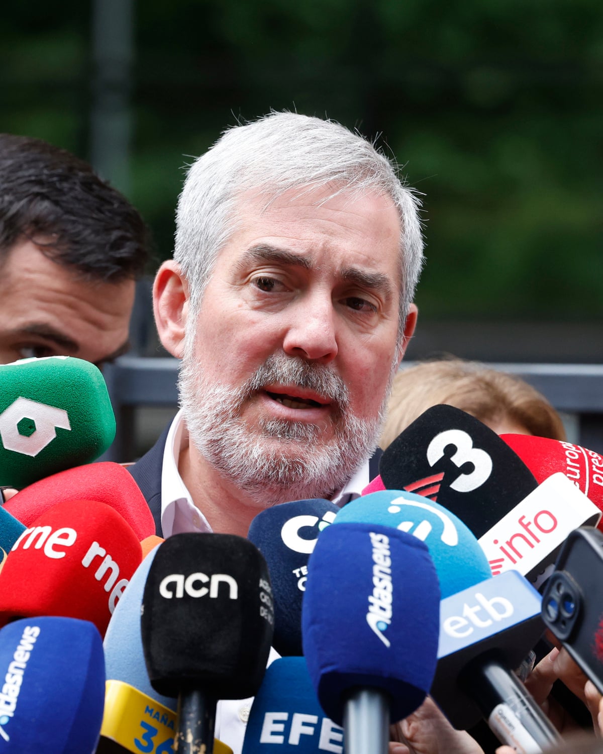 Fernando Clavijo speaks into a cluster of media-branded microphones 