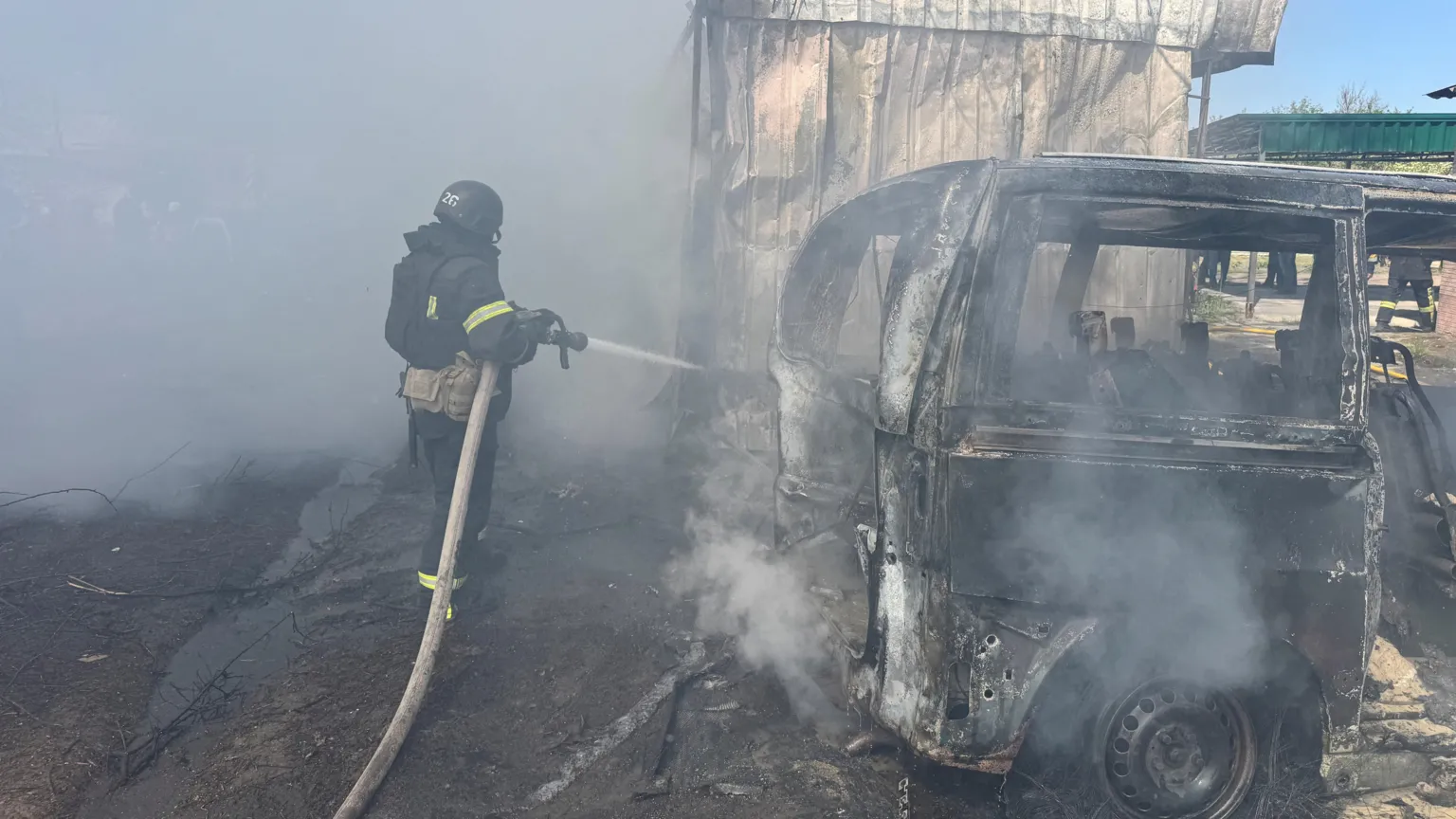  Firefighter trains hose on burnt-out vehicle in Kharkiv region of Ukraine on 7 May following Russian drone strike