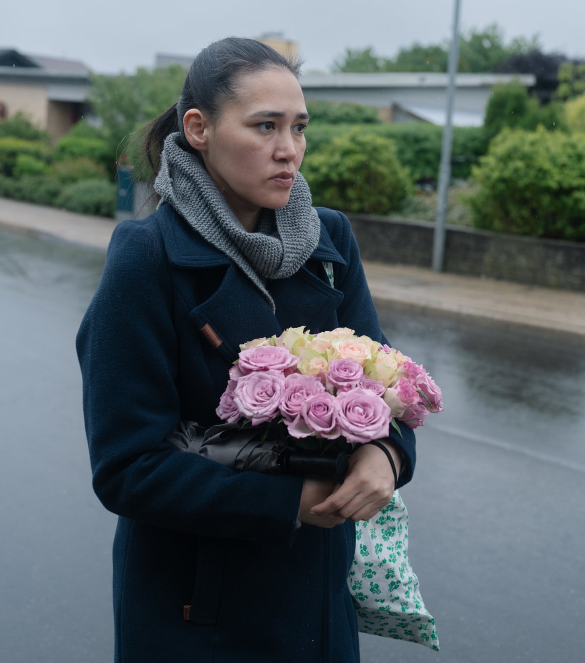 Keira Alexandra Kronvold stands in the street carrying a bunch of pink and yellow flowers.