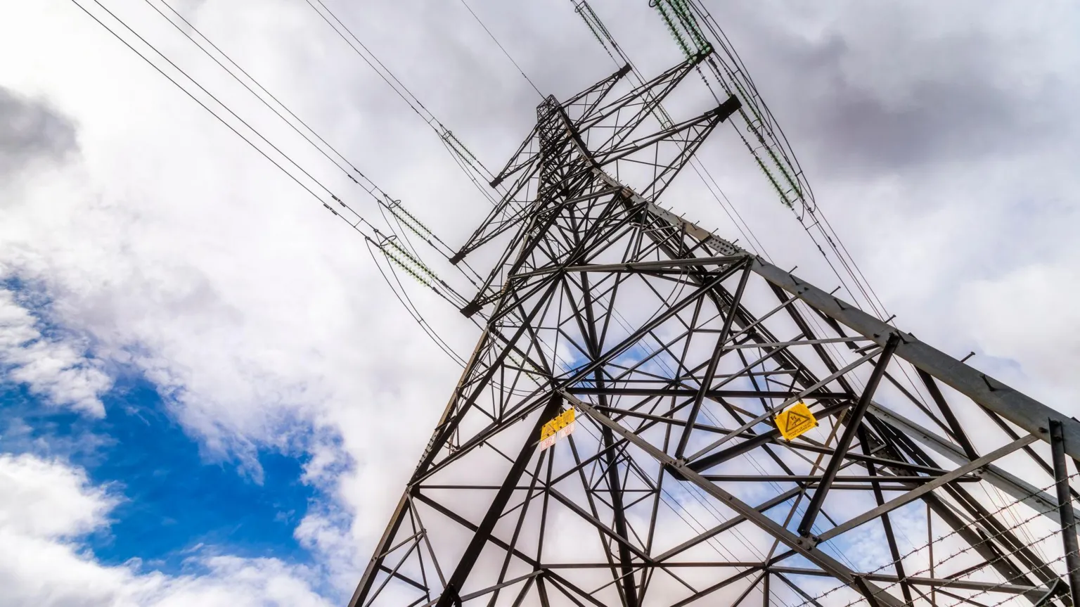  A metal electricity pylon stands tall into the sky. The sky is cloudy.