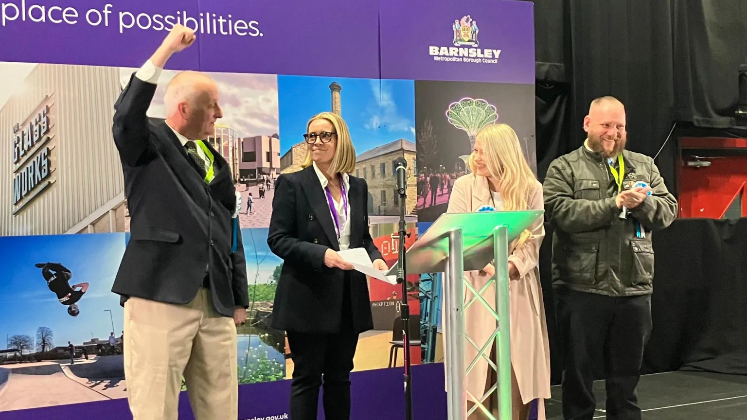 BBC/Victoria Scheer A group of four people standing on a raised stage. Behind them is a large purple backdrop featuring the text “Barnsley – the place of possibilities