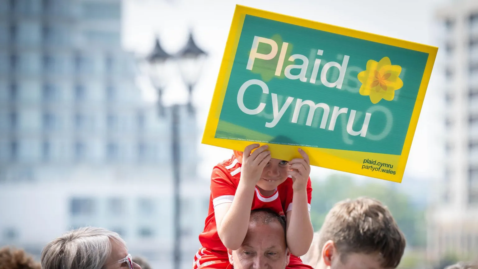Rob Norman/Plaid Cymru A young boy holding a Plaid Cymru banner on a man's shoulders.