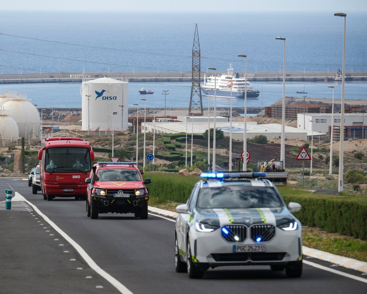 Military emergency vehicles drive in front of the coach transporting passengers to the airport