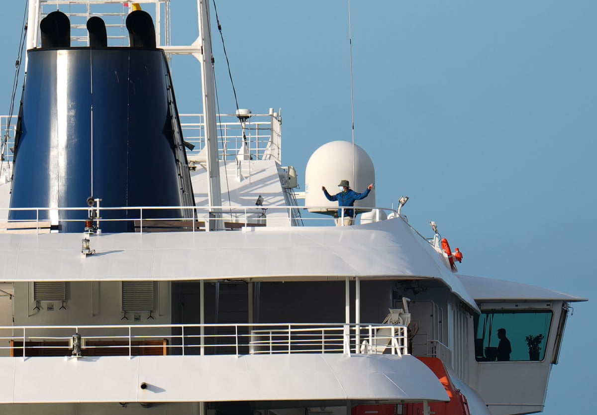 A man in a face mask and hat onboard the ship.