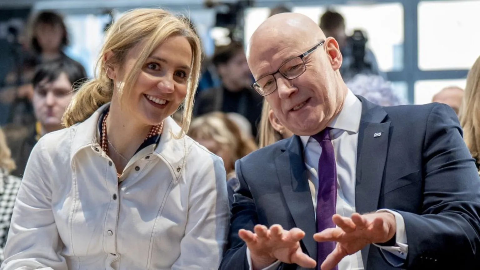  Mairi McAllan, who has blonde hair, and John Swinney, who is bald with glasses, smile as they speak to each other 