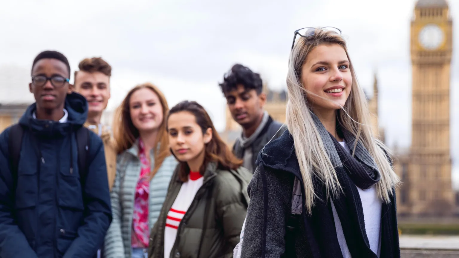 A group of teenagers pose for the camera against the backdrop of the Houses of Parliament