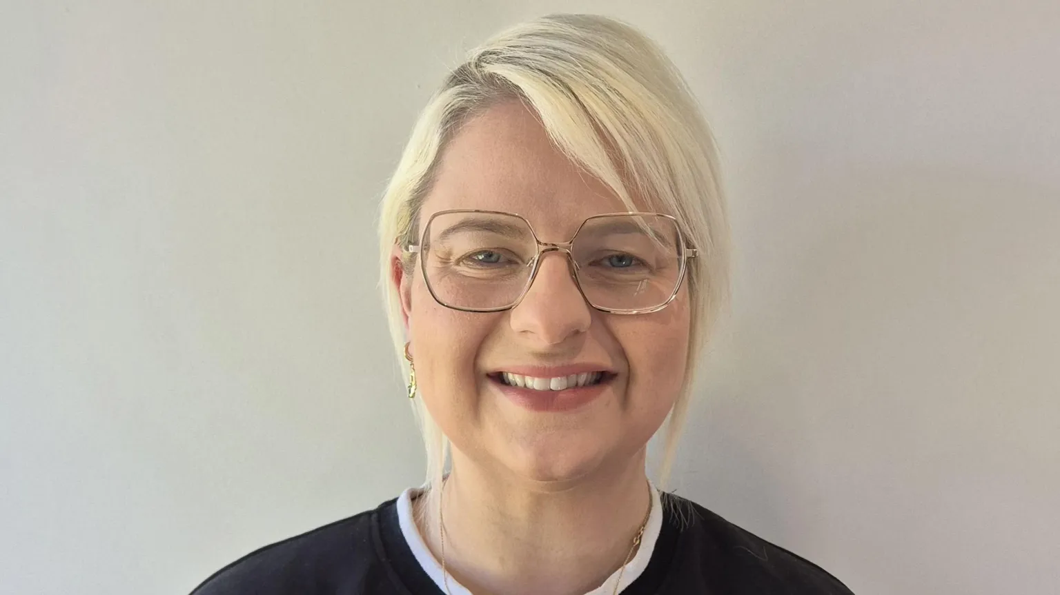 Laura McDermott Laura McDermott, a woman with short, blonde hair, smiles directly at the camera. She is wearing gold-rimmer glasses with wide lenses and black sweatshirt with a round white collar. 