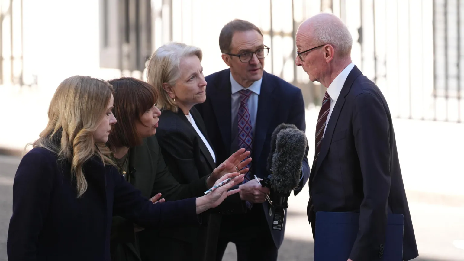 Four journalists hold out microphones in front of minister Pat McFadden
