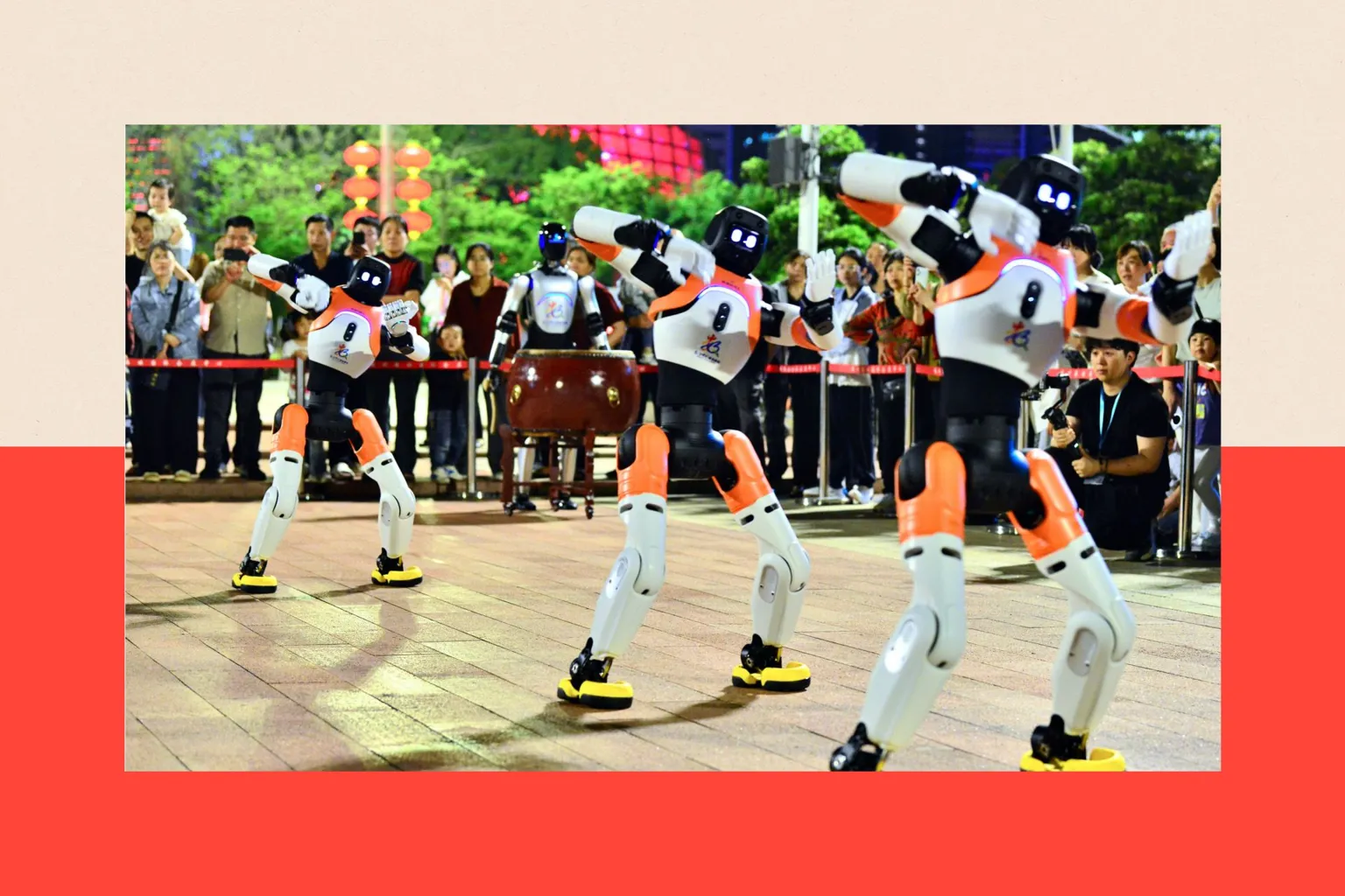 VCG via A row of three black, white and orange robots moving in formation, while a crowd of bystanders watch