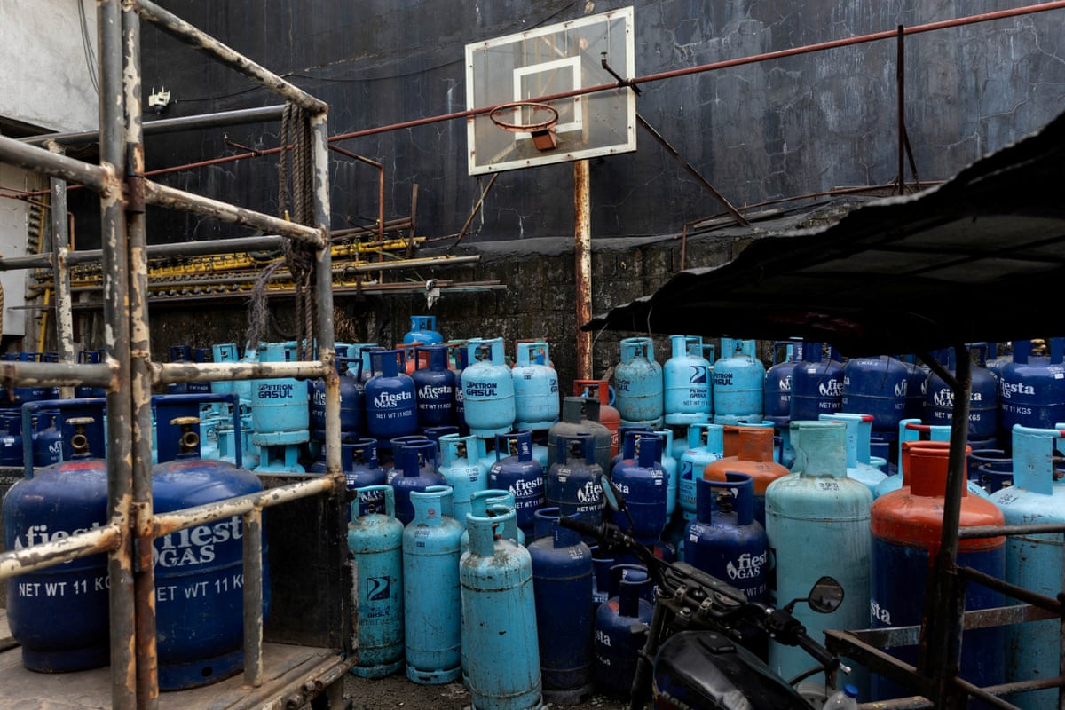 Dark blue, light blue and red LPG tanks are stacked in rows at a store.