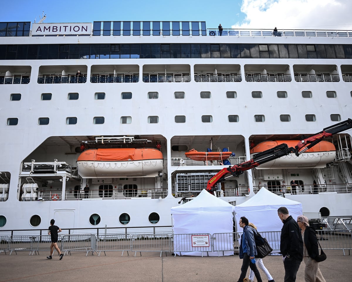 Passers-by walk past the Bahamas-registered cruise ship Ambition after passengers were confined following the outbreak of a gastrointestinal illness onboard, at the Bordeaux port in southwestern France.
