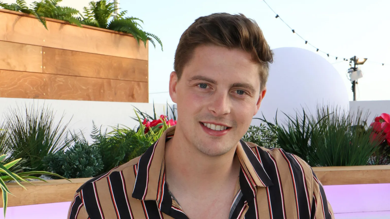  Alex George, wearing a brown and blue striped top