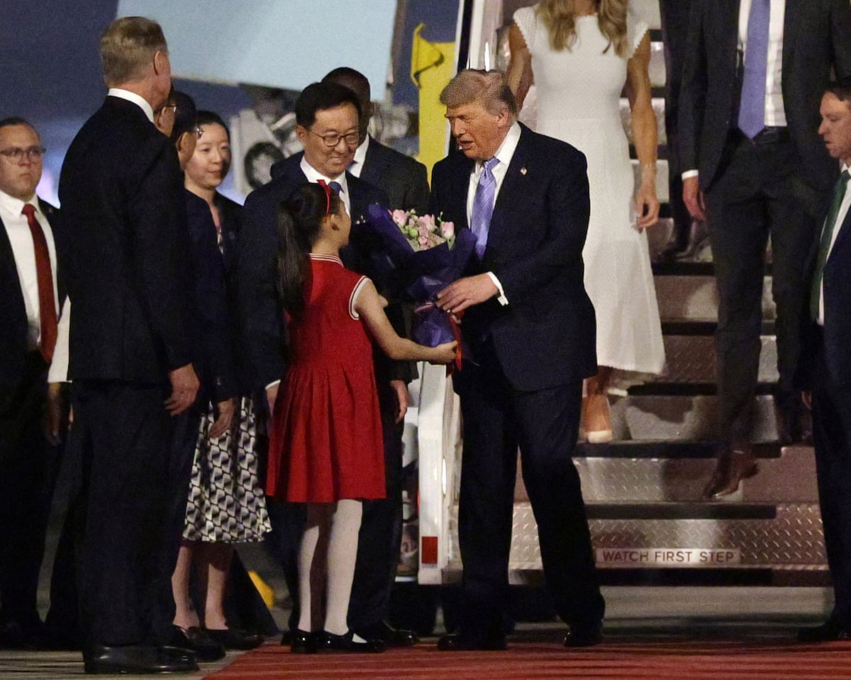 Trump receives a flower bouquet from a young girl beside Chinese vice-president Han Zheng on the red carpet
