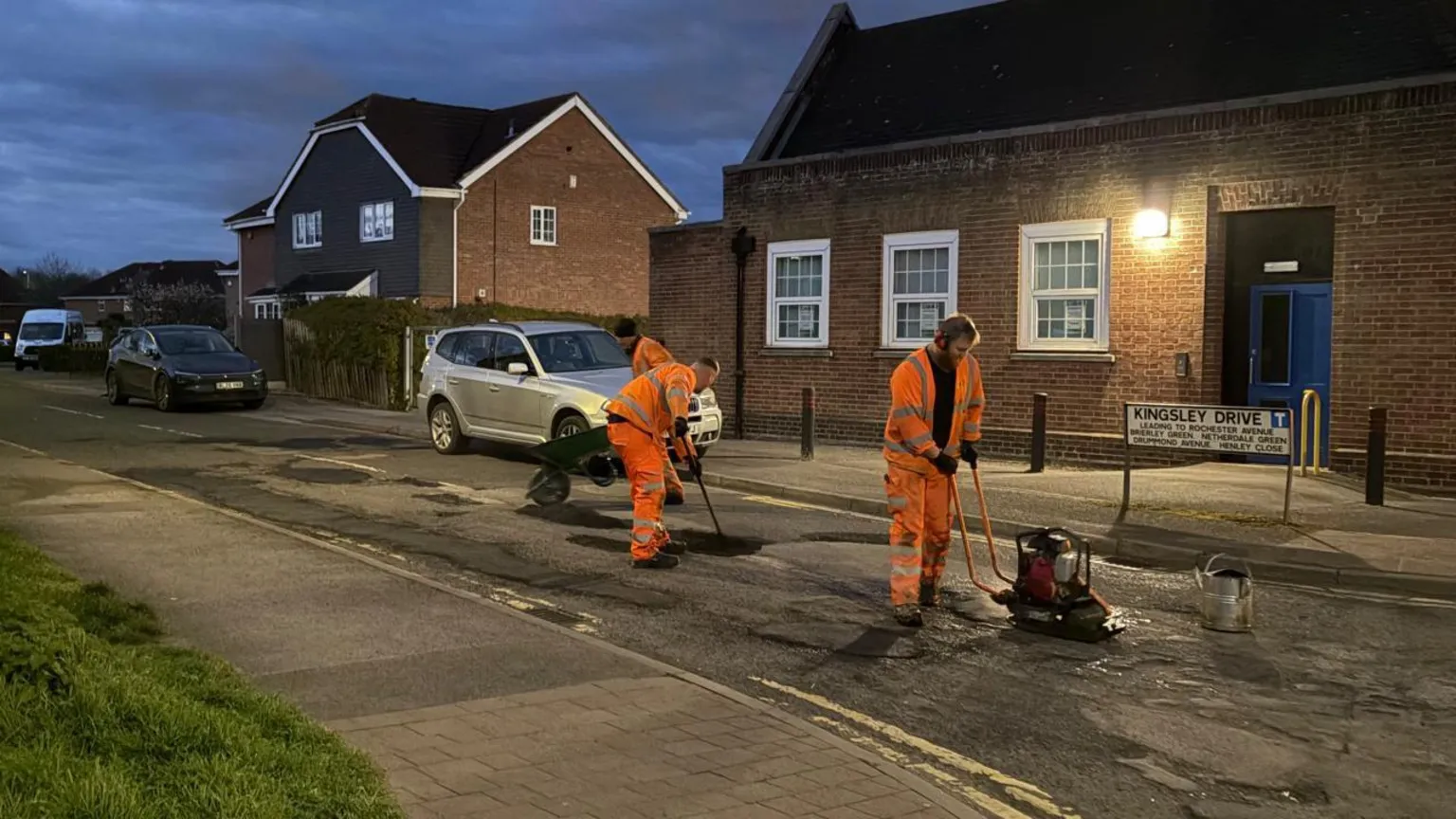 Highway maintenance workers wearing hi vis and resurfacing a road in Netherfield, Nottinghamshire.