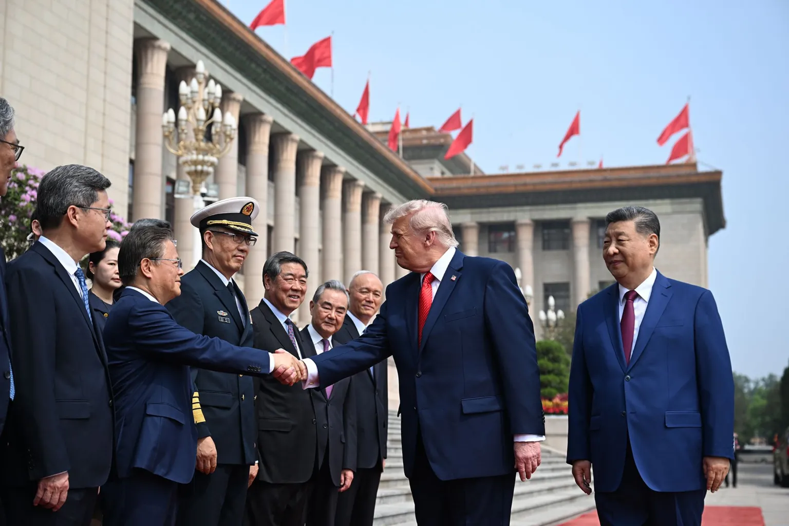 U.S. President Donald Trump trailed by Chinese President Xi Jinping greets other officials at the Great Hall of the People on May 14, 2026 in Beijing, China