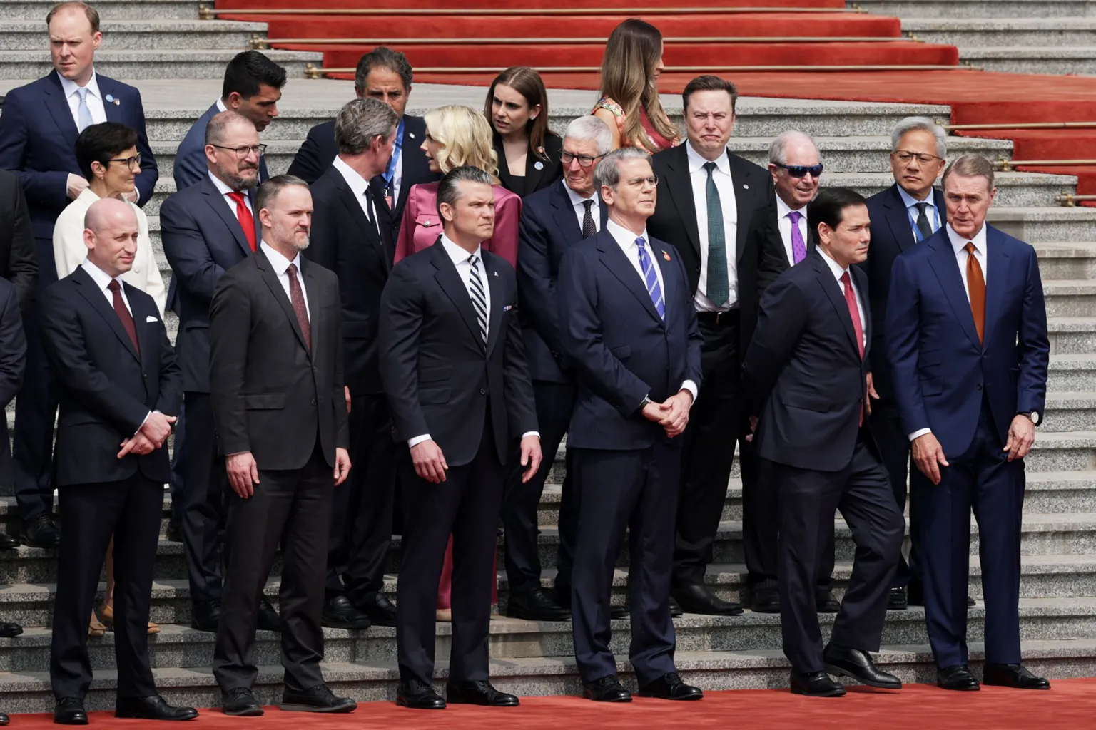 Members of the U.S. delegation including (front L-R) White House Deputy Chief of Staff Stephen Miller, Trade Representative Jamieson Greer, Secretary of War Pete Hegseth, Secretary of the Treasury Scott Bessent, Secretary of State Marco Rubio, Ambassador to China David Perdue, and CEOs from various industries including Apple CEO Tim Cook, Tesla CEO Elon Musk and Nvidia CEO Jensen Huang, stand prior to a welcome ceremony for U.S. President Donald Trump at the Great Hall of the People on May 14, 2026 in Beijing, China.