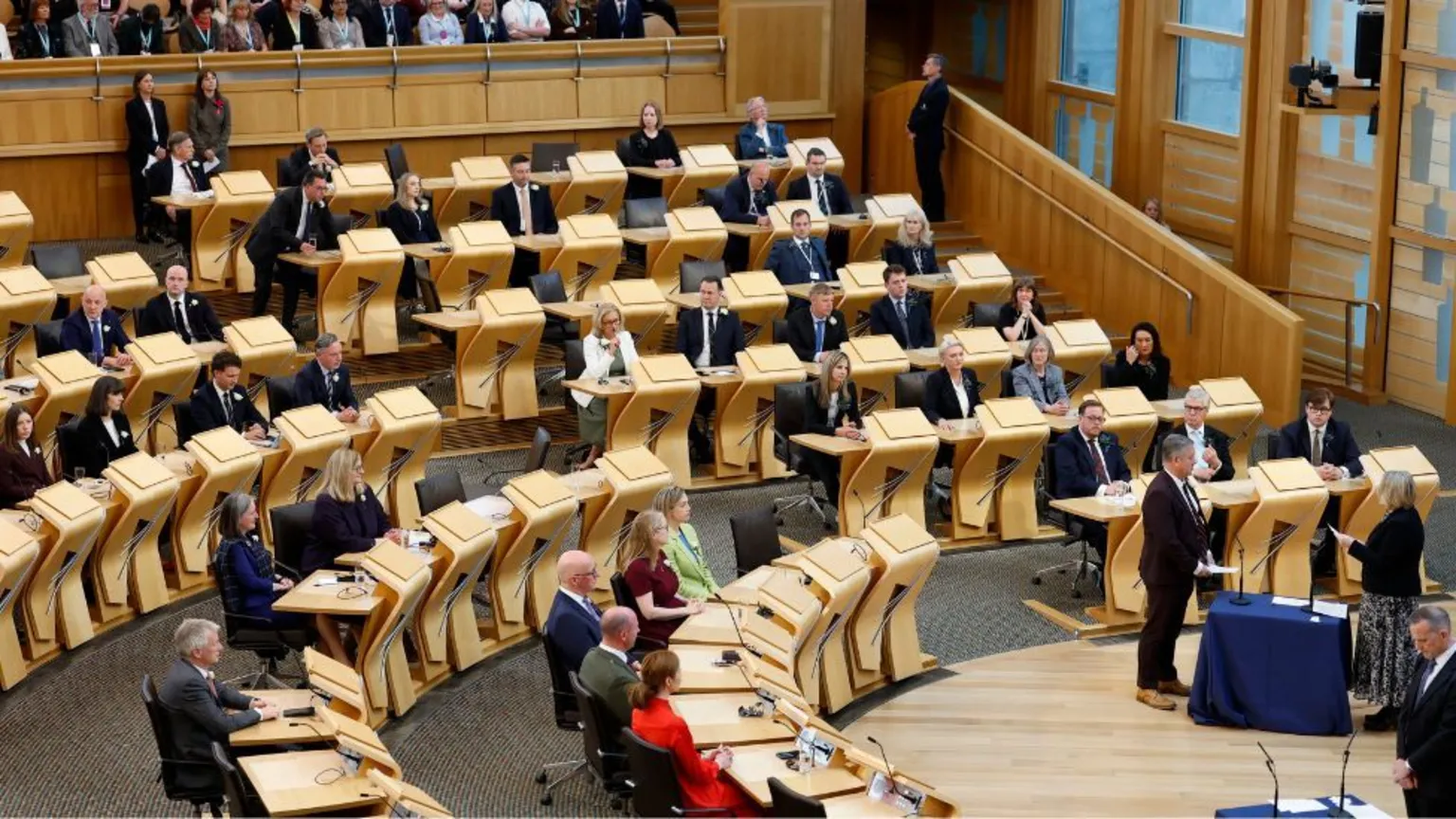 A wide view of the Holyrood chamber, with MSPs sat at wooden desks