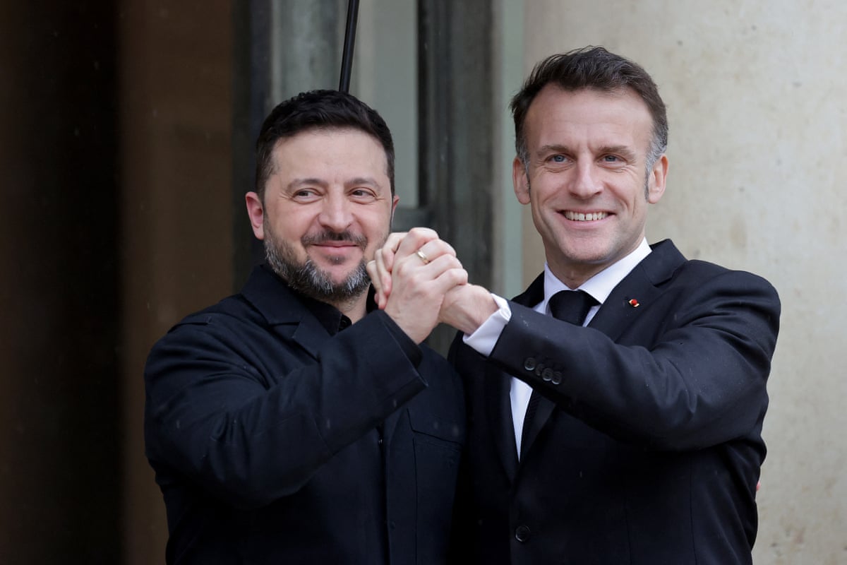 Emmanuel Macron holds hands with Ukrainian president Volodymyr Zelenskyy for the cameras. 
