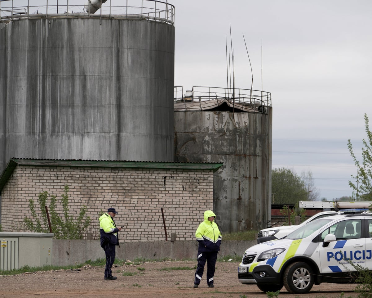 Police officers stand at the site of damage after drones crashed at a storage facility in Rezekne, Latvia.