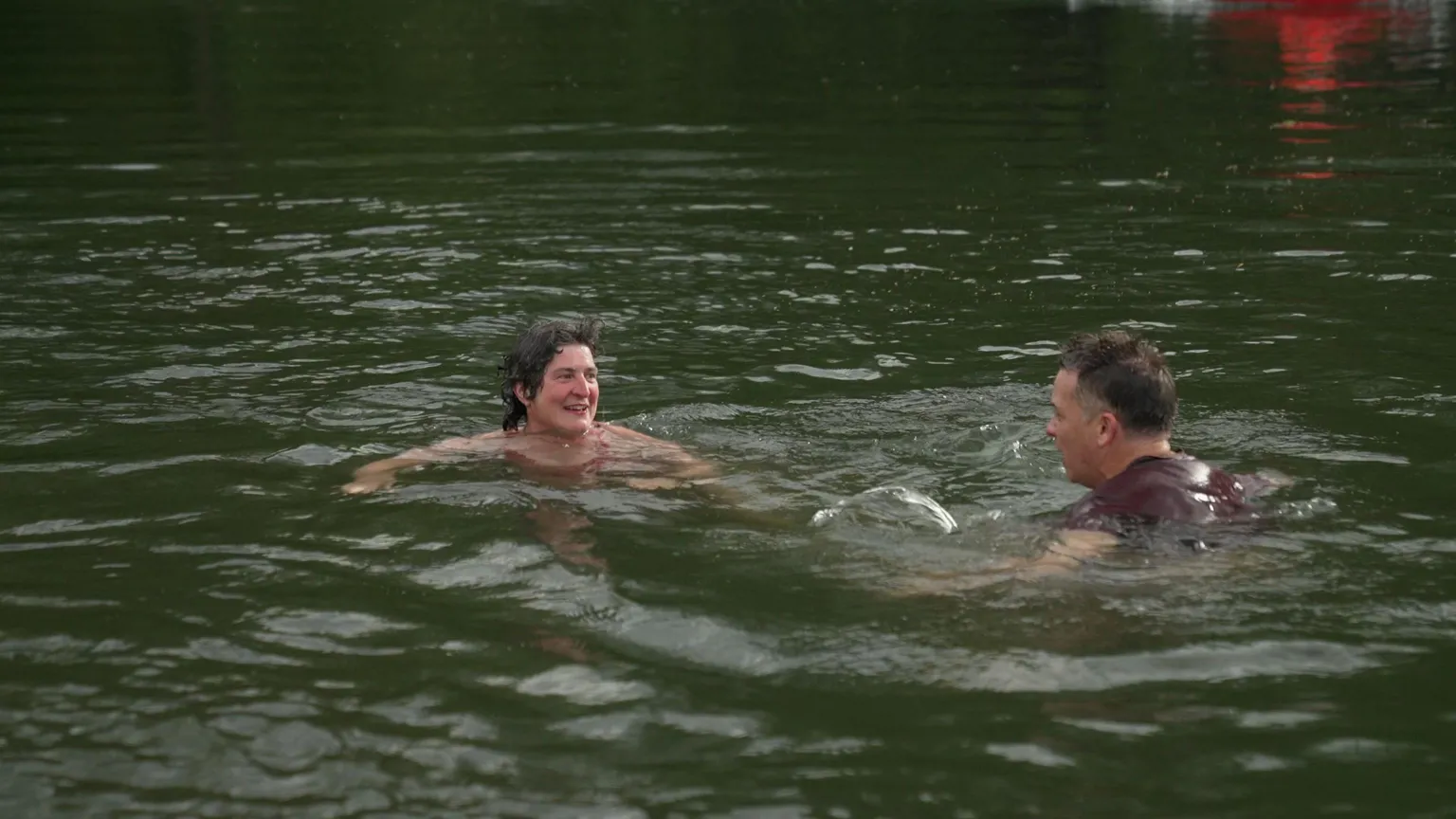 Two swimmers talk to each other in the River Teme.